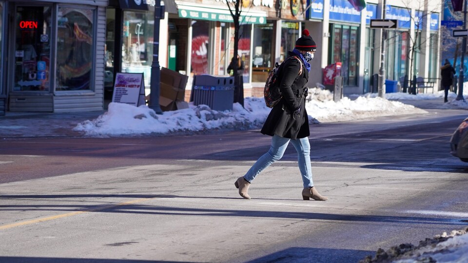 Une femme portant le masque traverse la rue à Ottawa.