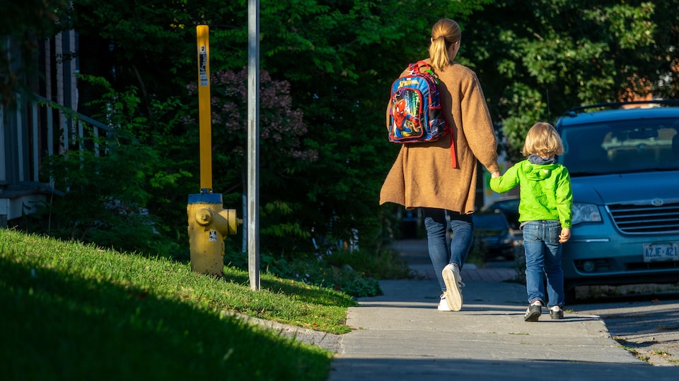 Une femme marche avec un enfant en lui tenant la main.