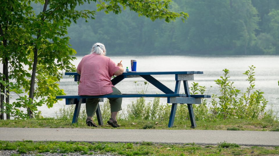 Une femme est assis à une table de piquenique près de la rivière.