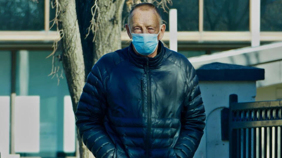 Un homme marche dans la rue en portant un masque.