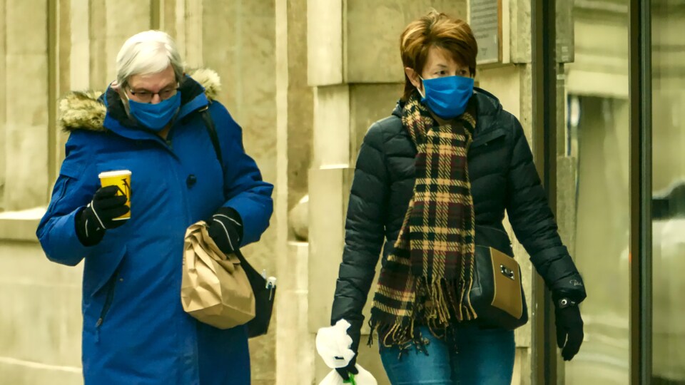 Des gens portant des masques à l'extérieur en hiver, pendant la pandémie de la COVID-19 à Regina, en Saskatchewan.