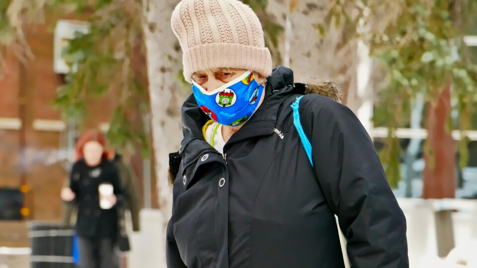 Une personne portant des vêtements d'hiver porte un couvre-visage.