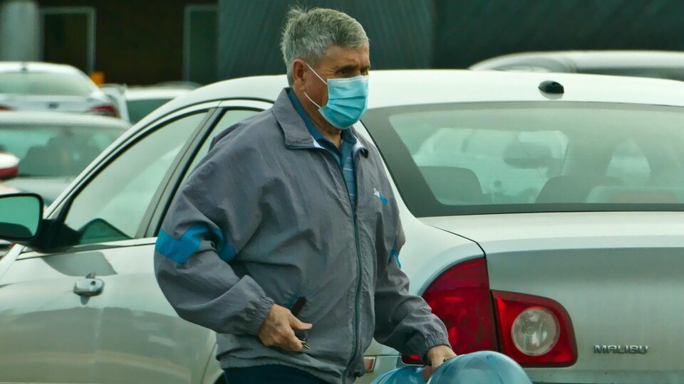 Un homme portant un masque contre la COVID-19 et une veste d'automne.