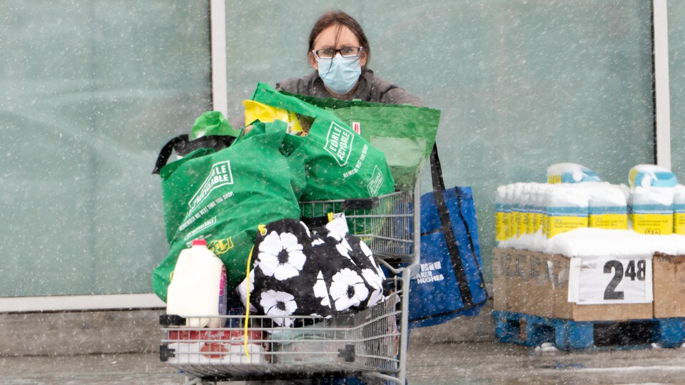Une femme porte un masque à l'extérieur pendant la pandémie de la COVID-19 à Regina en hiver.