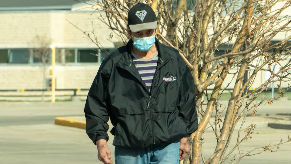 Un homme porte un masque en marchant dans la rue.
