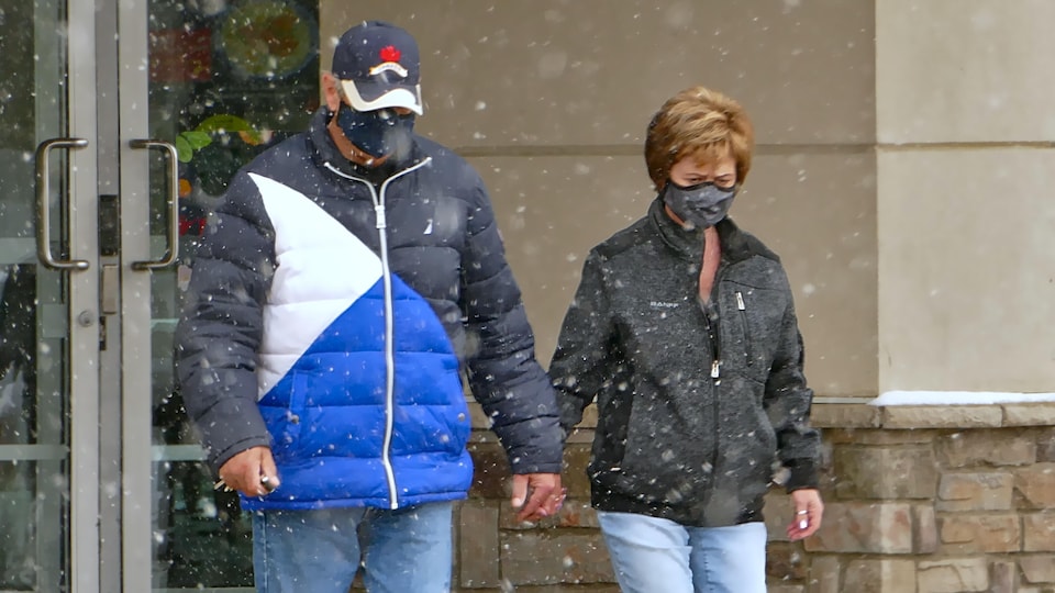 Un couple portant chacun un masque marche main dans la main