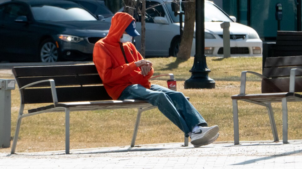 Un homme assis sur un banc public.