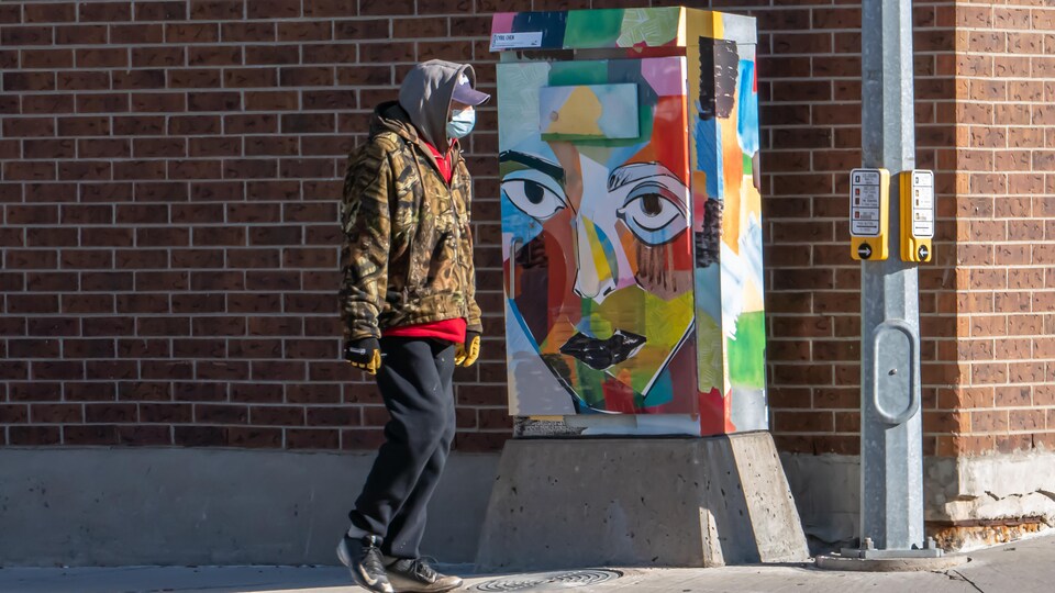 Un homme à l'extérieur de Regina qui porte un masque.