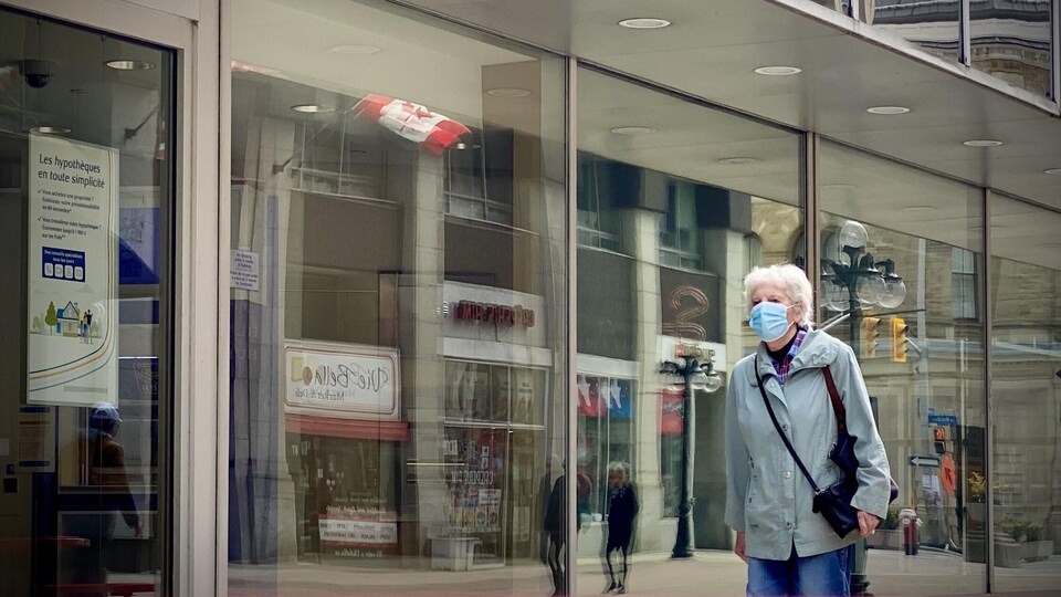 Une personne portant le masque marche dans la rue.