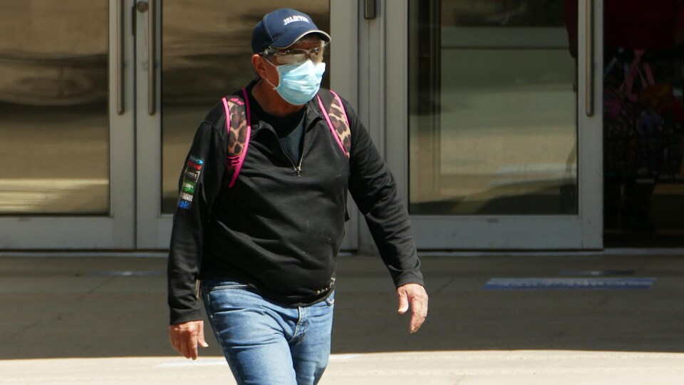 Un homme marche avec un masque sur son visage.