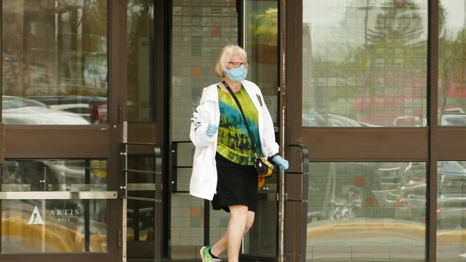 Une femme marche dans les rues de Regina en portant un masque.