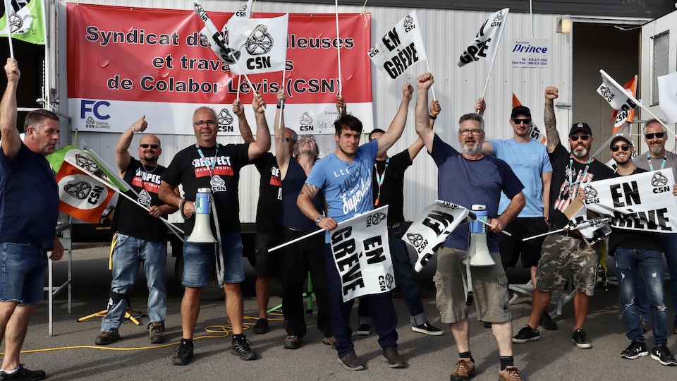 Une douzaine de grévistes avec des affiches de la CSN.