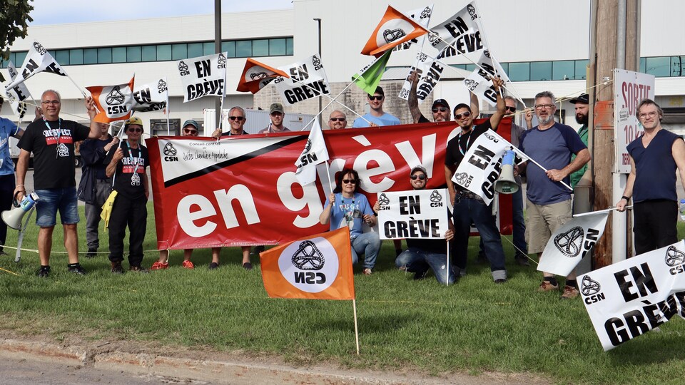Des travailleurs brandissent des pancartes indiquant «En grève».