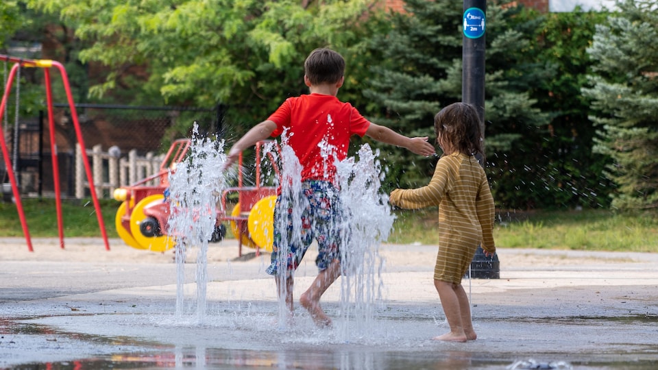 Des enfants jouent dans un parc à jets d'eau.