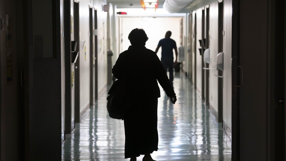 Un femme marche dans un corridor d'hôpital.
