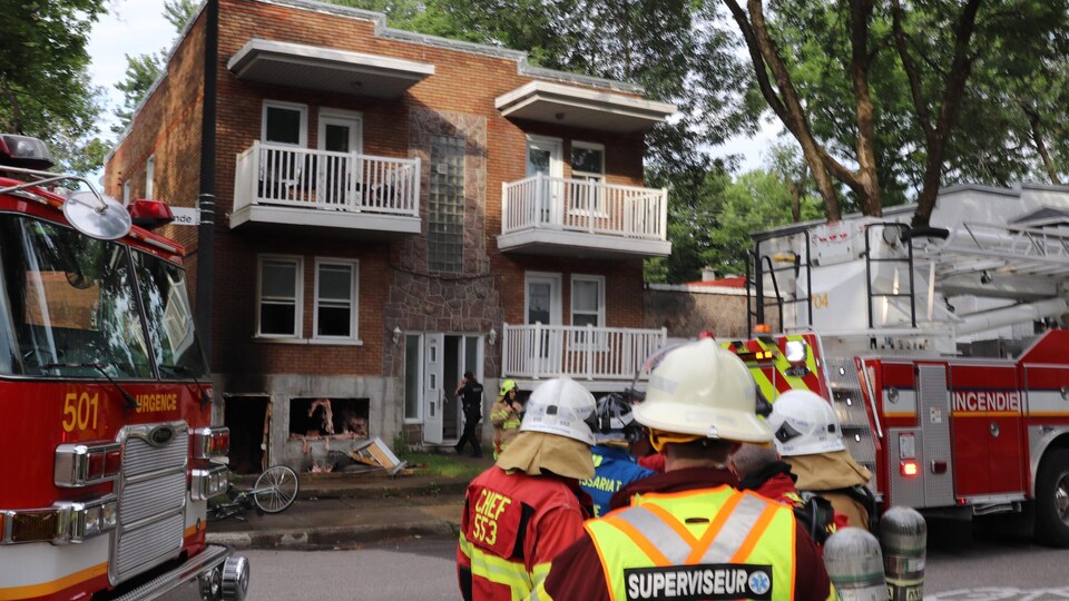 Des pompiers devant un immeuble ravagé par le feu.