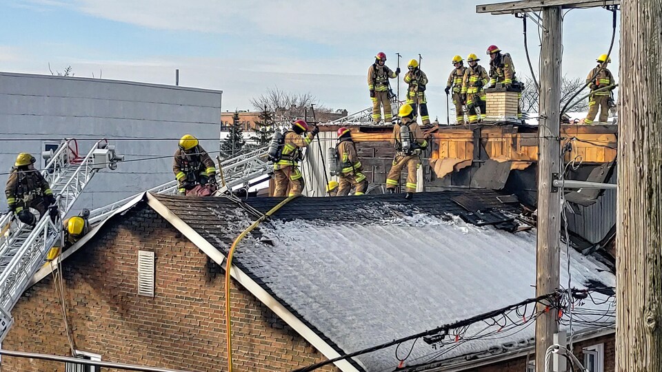 Des pompiers sur le toit inspectent le bâtiment.