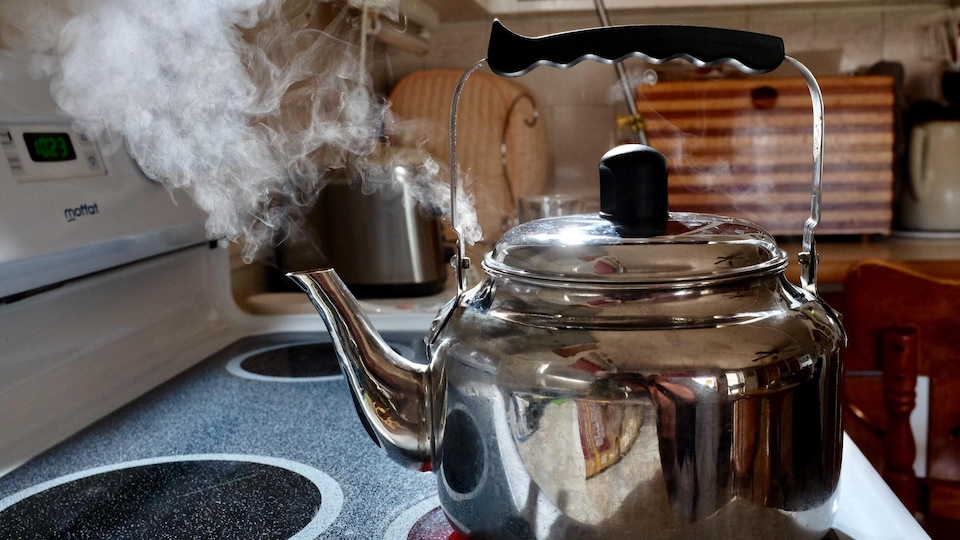 De la vapeur sort d'une bouilloire sur une cuisinière. 