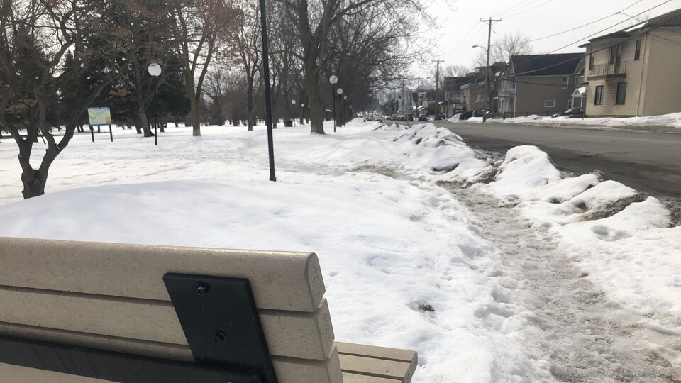 Un banc devant une rue, en hiver.