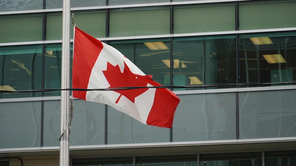 Le drapeau du Canada devant un immeuble.