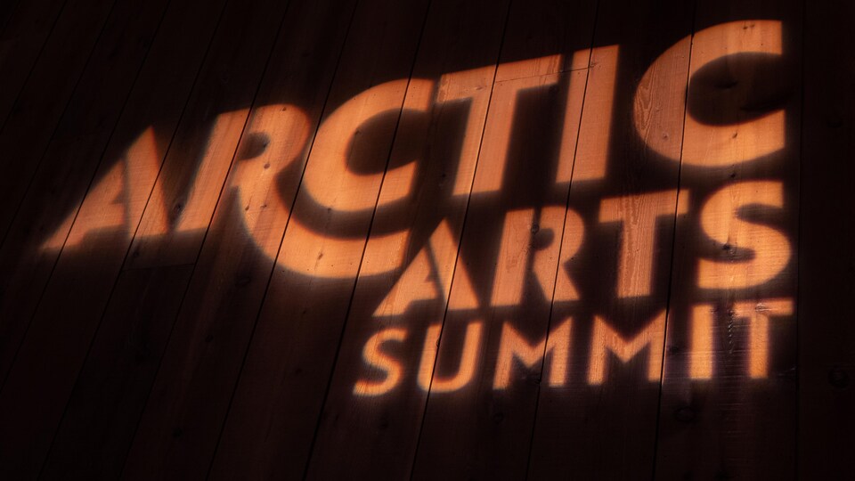 Le logo du sommet est projeté sur un mur en bois.