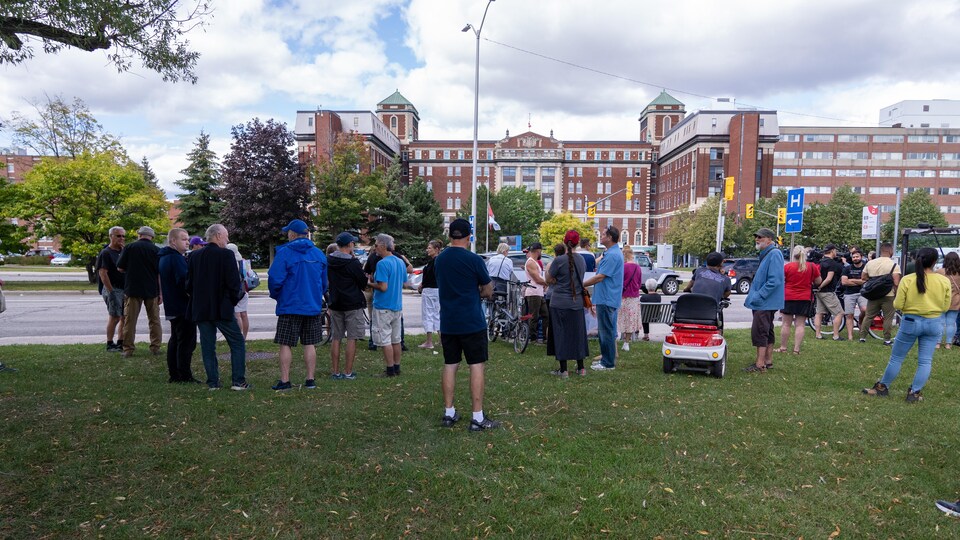 Des gens rassemblés dehors devant un hôpital.