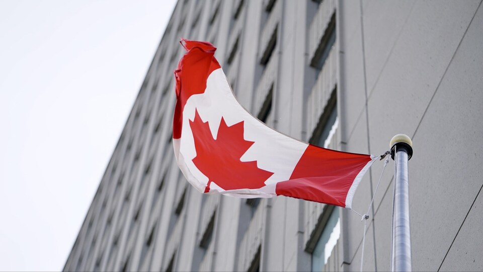 Le drapeau du Canada vogue devant l'édifice.
