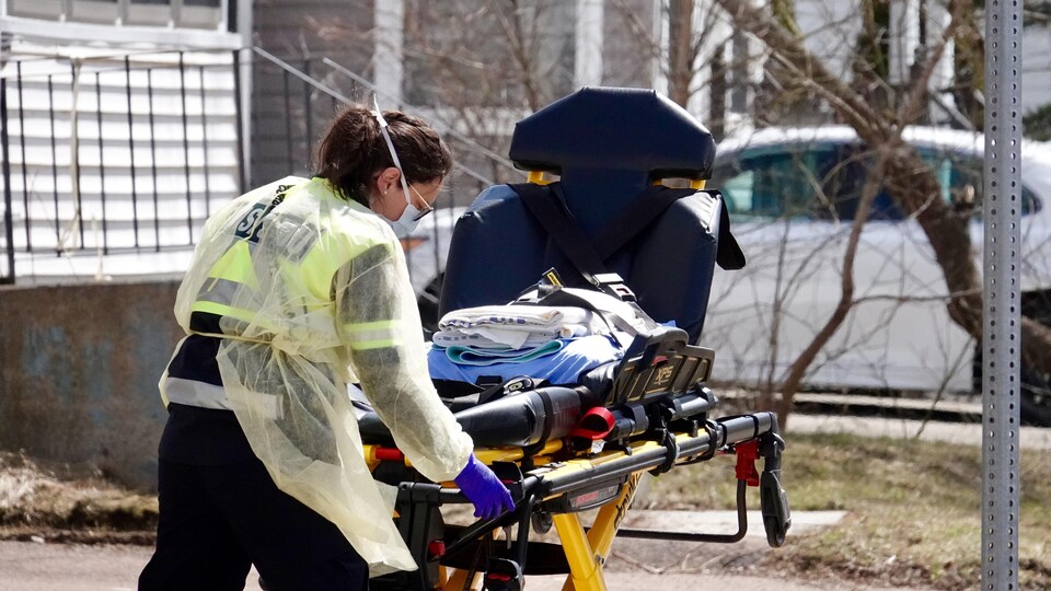 Une ambulancière pousse une civière vide.