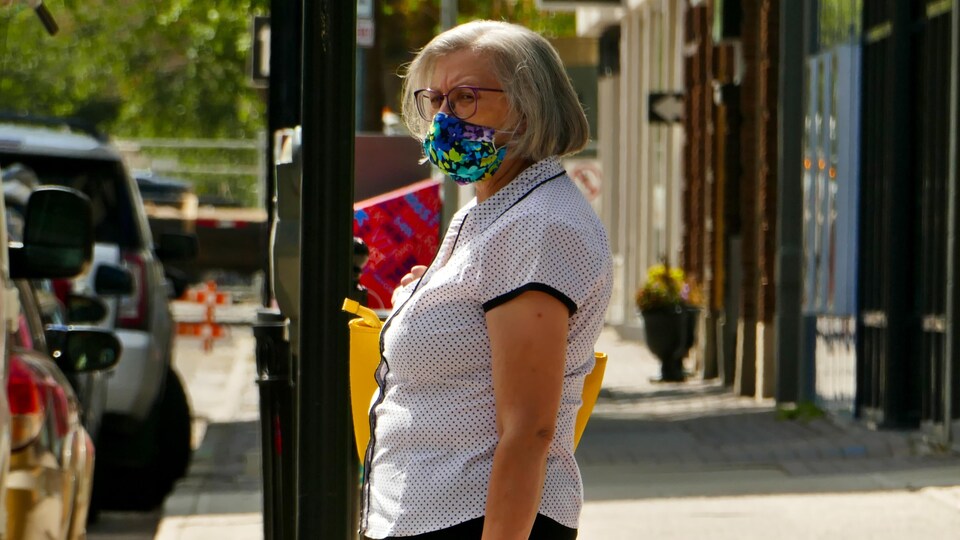 Une femme porte un masque à l'extérieur pendant la pandémie de la COVID-19 à Regina en l'été. (archives)