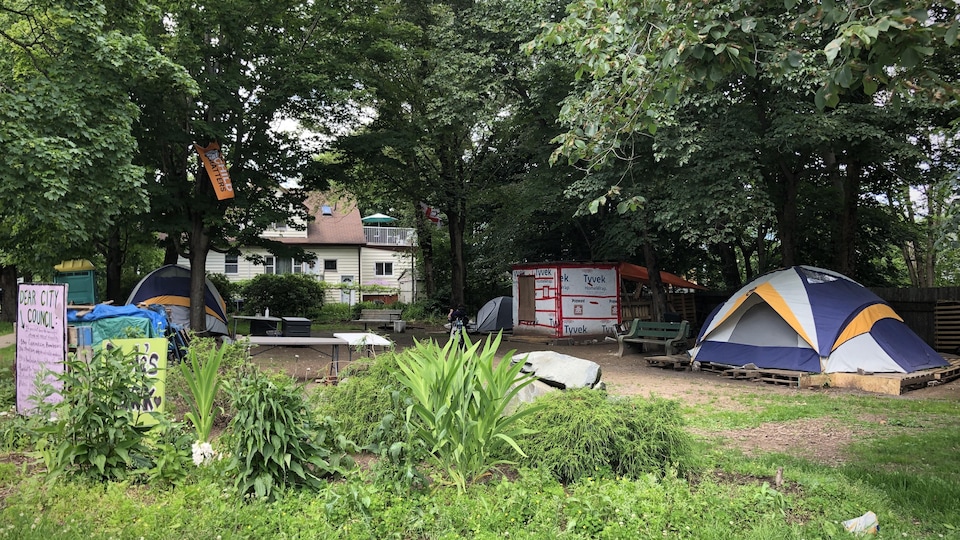 Des tentes et des cabanes dans un petit parc au coin d'une rue, en été.