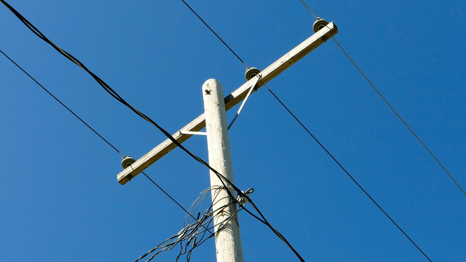 Des lignes électriques aériennes, sur un poteau électrique, à l'extérieur, sous un ciel dégagé.