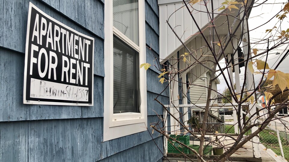 Une pancarte d'appartement à louer affichée sur une maison bleue.