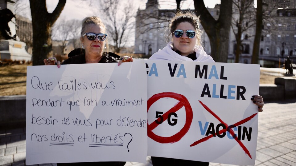 Deux manifestantes portent des pancartes sur lesquelles est écrit : « Que faites-vous pendant que l’on a vraiment besoin de vous pour défendre nos droits et libertés » et « Ça va mal aller ».