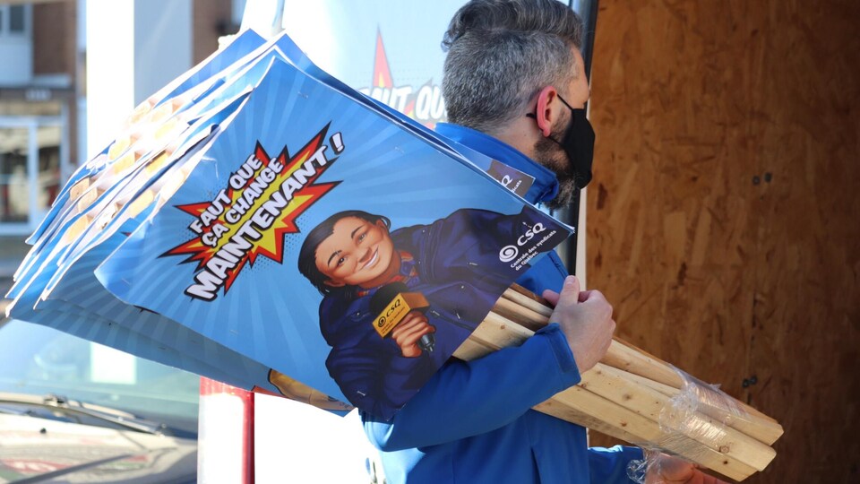 Une personne tient dans ses mains plusieurs pancartes.