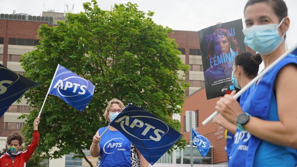 Des manifestants, portant du bleu, avec des drapeaux syndicaux de la même couleur.