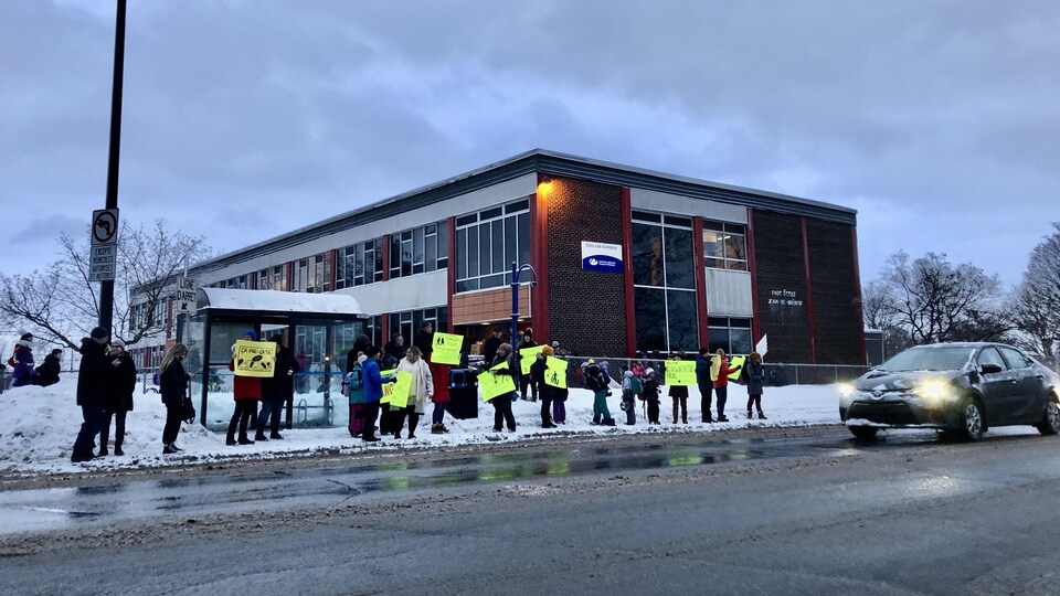 Des parents manifestent devant une école.