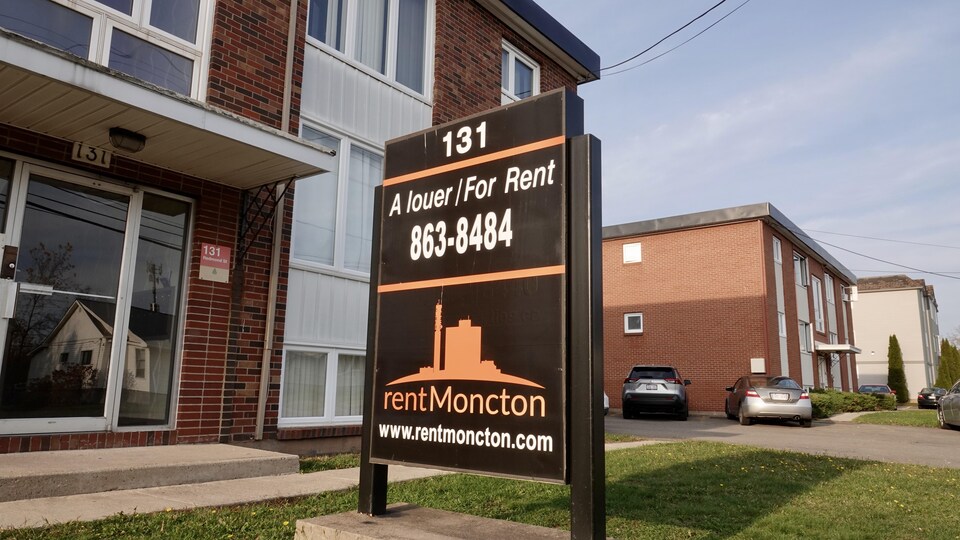 Affiche de logement à louer devant un immeuble d'habitation.