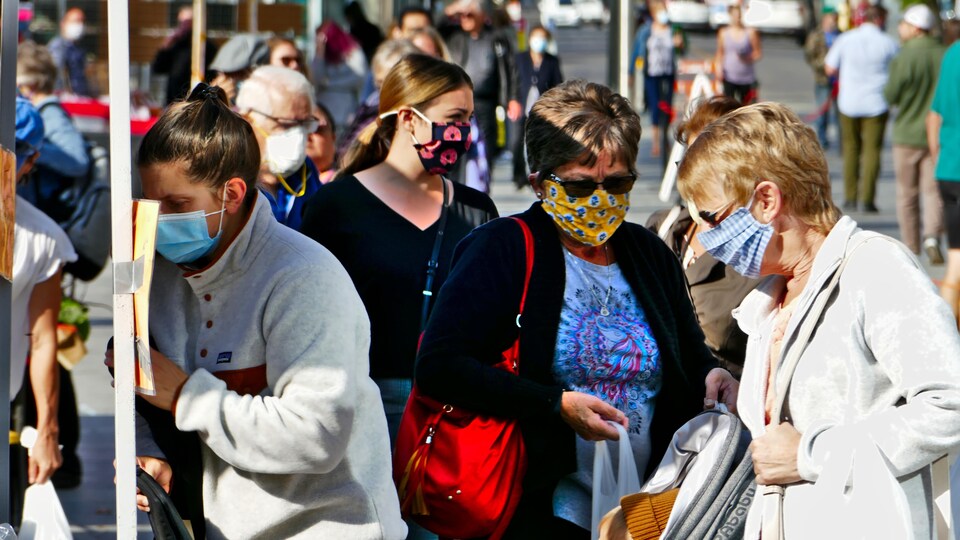 Des gens portant des masques au marché des fermiers de Regina en automne.