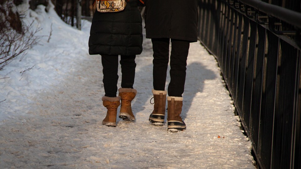 Les jambes et les bottes d'un homme et d'une femme qui marchent sur la promenade enneigée.
