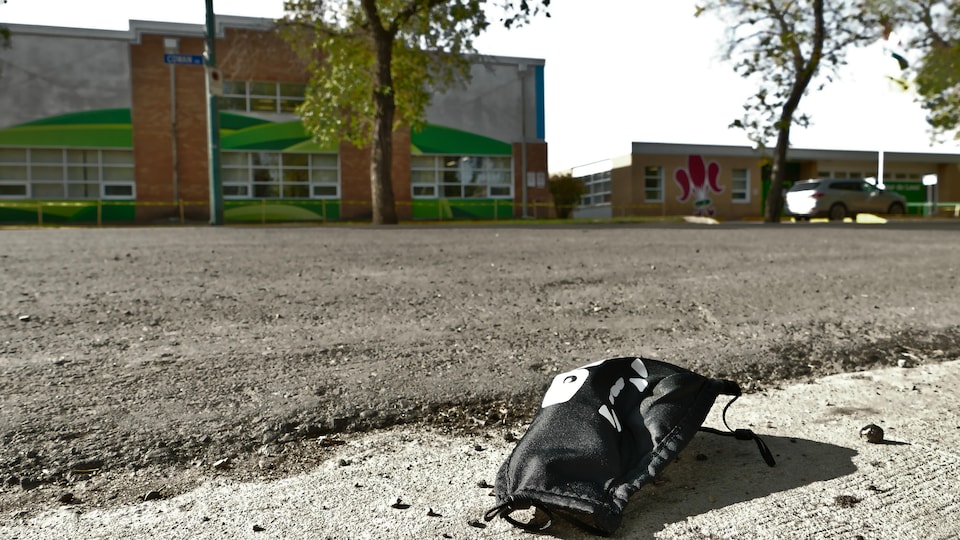 Un masque noir pour enfant est par terre dans la rue devant l'École élémentaire Monseigneur-de-Laval à Regina.