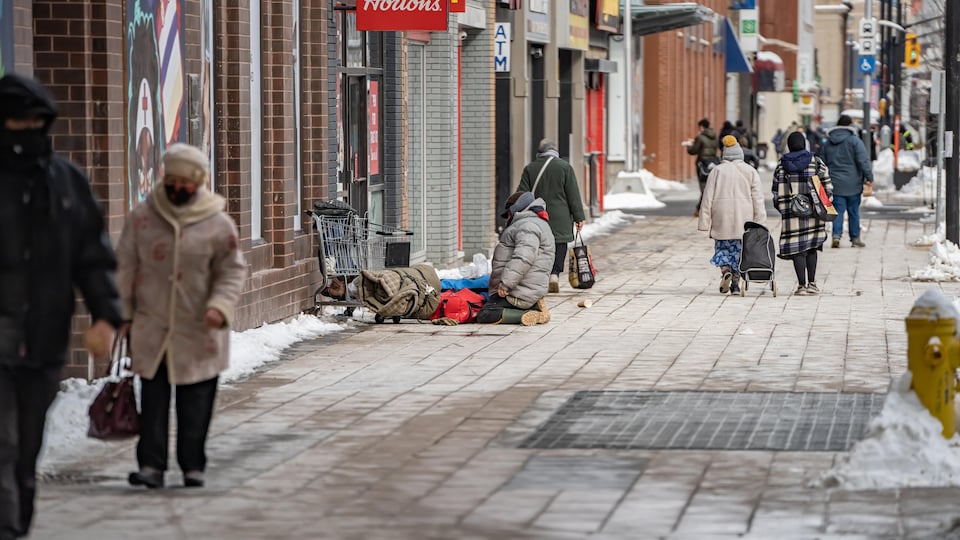 Un itinérant sur ses genoux, à la sortie d'un café d'Ottawa.