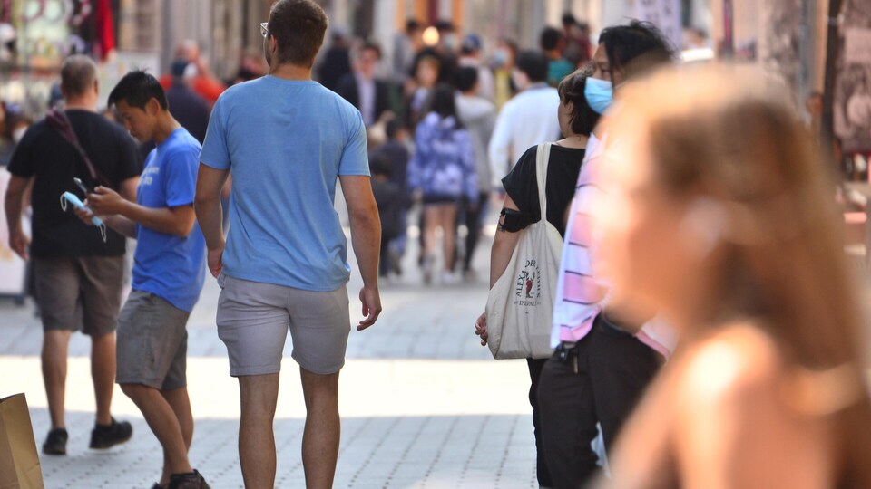 Beaucoup de personnes déambulent sur une rue piétonne.