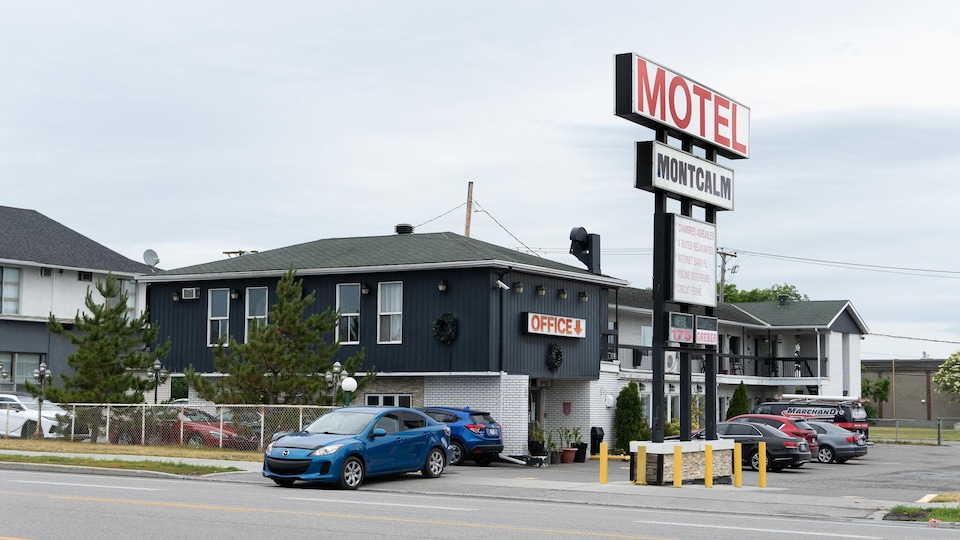 Un motel vu de l'extérieur avec des voitures stationnées devant.