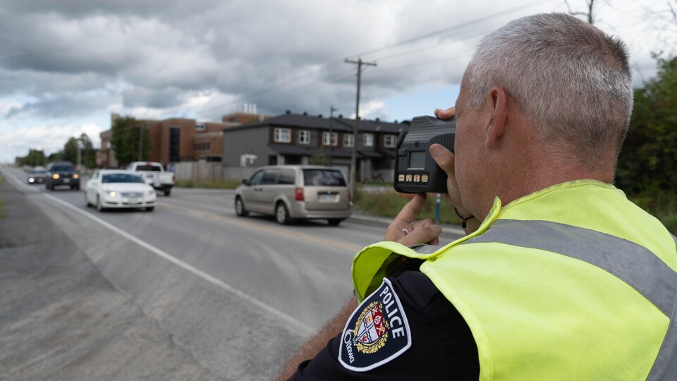 Un policier calcule la vitesse des automobiles à l'aide d'un radar qu'il pointe dans leur direction.
