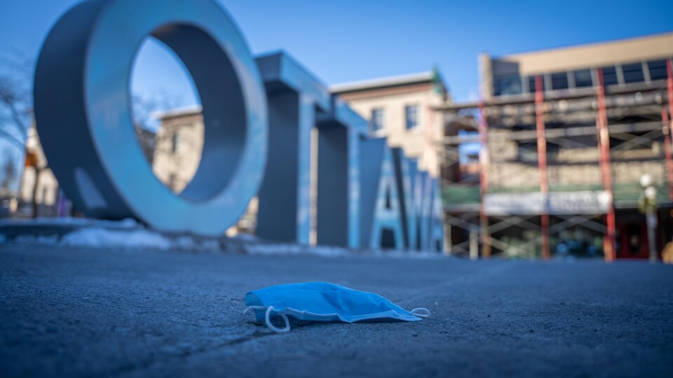 Un masque chirurgical sur le sol près de grosses lettre « OTTAWA ».