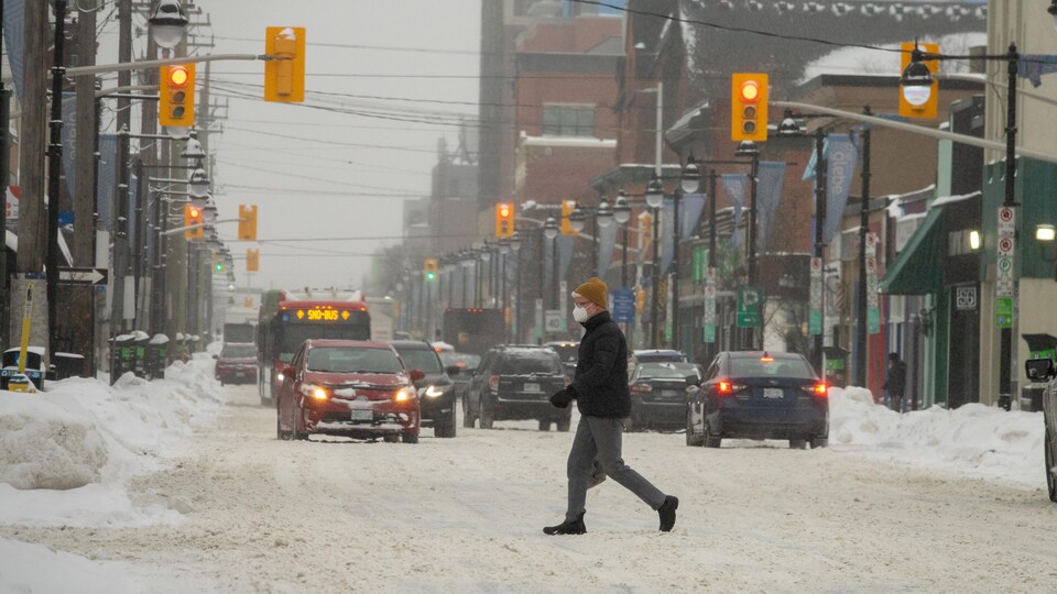 Un homme traverse une rue enneigée d'Ottawa.