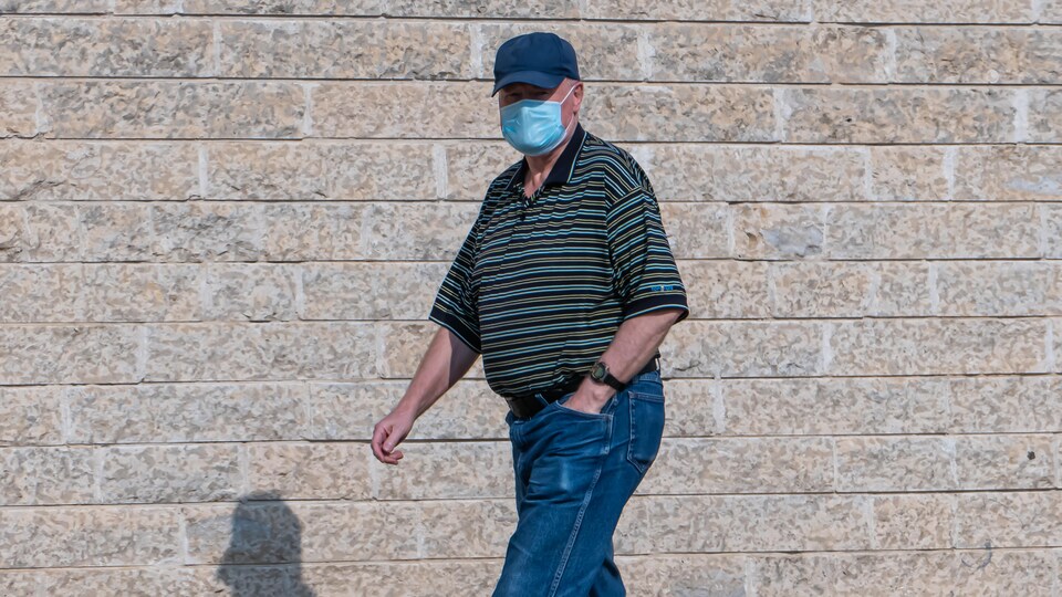 Un homme porte un masque à l'extérieur pendant la pandémie de la COVID-19 