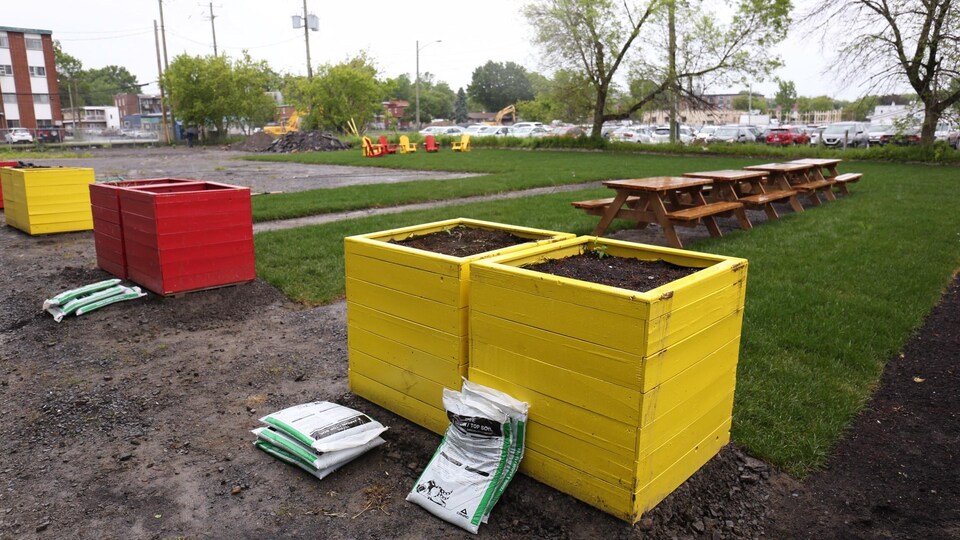 Des bancs rouges et jaunes pour mettre des fleurs installés dans un espace vert