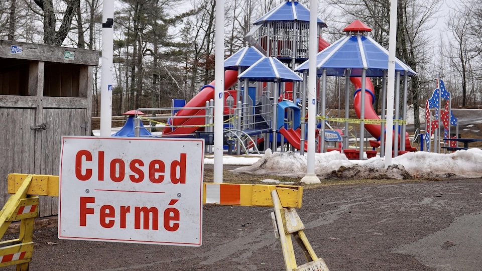 Une affiche temporaire à l'entrée d'un parc de jeux pour enfant indique la fermeture des lieux.