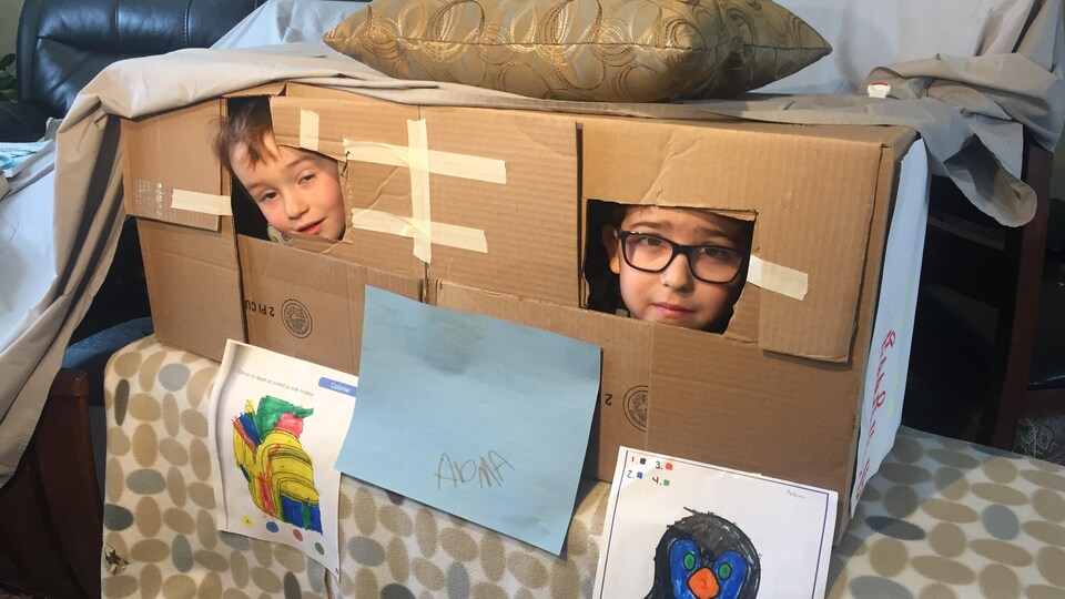Deux jeunes sont dans une cabane en carton.